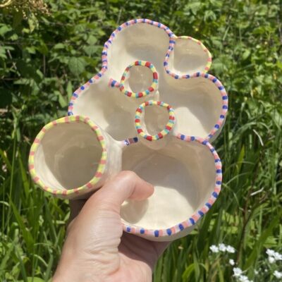 Handcrafted multi-compartment ceramic paint palette with colorful hand-painted striped rims.